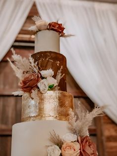 a three tiered wedding cake with flowers and feathers