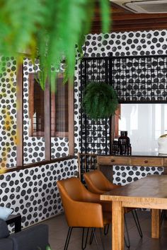 a dining room with black and white wallpaper, leather chairs and a wooden table