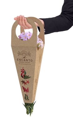 a person holding a paper bag with flowers in it and the tag attached to it that says encanto