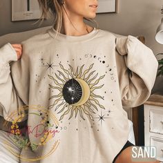 "Celestial Mystical Sun and Moon Crewneck Sweatshirt with Seeing Eye, Spiritual Sun and Moon Sweatshirt, Witch Clothing Astrology Sweatshirt, Festival Shirt, Festival Sweatshirt, Aesthetic Spiritual Celestial Crewneck Shirt, Boho Sun and Moon Sweatshirt, Witchy clothing, Dark Academia Clothing, Moon Phase Sweatshirt. The Gildan 18000 crewneck sweatshirt is a stunning piece of wearable art that combines celestial and mystical elements to create a unique and captivating design. At the center of the sweatshirt, a brilliantly detailed sun and moon design blend seamlessly together, representing the duality and balance of the universe. This sun and moon with seeing eye sweatshirt is a versatile piece of clothing that can be a great addition to anyone's wardrobe. It's suitable for both men and wo Astrology Clothes, Moon Clothing, Baggy Shirt, Dark Academia Clothing, Festival Shirts, Moon Design, Indie Fashion, Crew Neck Shirt, Dream Clothes