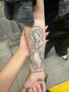 a woman with a tattoo on her arm holding onto another person's hand while they both hold their hands together