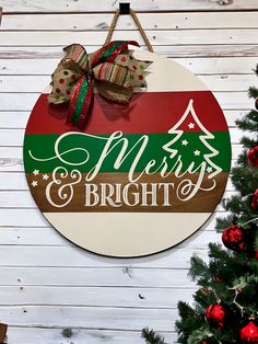 a merry and bright sign hanging on the side of a wooden wall next to a christmas tree