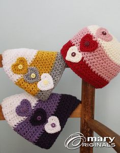 two crocheted hats are sitting on a chair