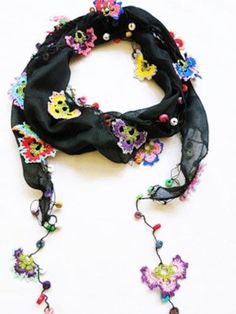 a black scarf with colorful flowers and skulls on the end is laying on a white surface