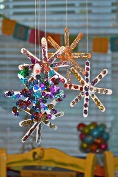 two snowflakes hanging from strings in the middle of a dining room table