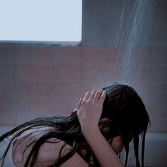 a woman in the shower with her hands on her head and water coming out of her hair