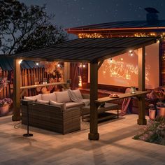 a covered patio area with couches and lights on the outside wall, at night