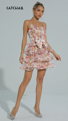 a woman wearing a dress with flowers on it and heels standing in front of a white background