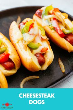 three hot dogs with toppings on a black plate