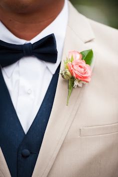 a man in a suit and bow tie with a boutonniere on his lapel