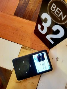 a cell phone sitting on top of a wooden table next to a sign that says ben