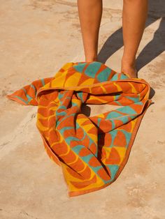 a person standing next to a towel on the ground with their feet in the sand