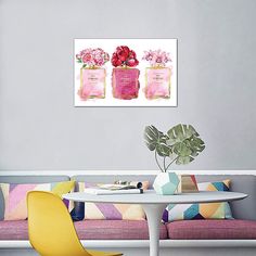 three pink perfume bottles with flowers in them sitting on a table next to a couch