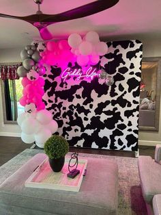 a living room filled with furniture and balloons on the ceiling above it is a cow print wall