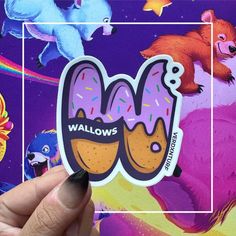 someone holding up a sticker with the word wallows on it in front of a colorful background