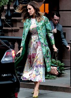 a woman in a dress and coat walking down the street