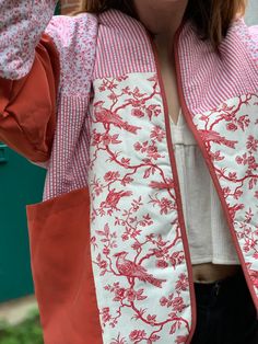 a woman wearing a red and white jacket with pink flowers on it's sleeves