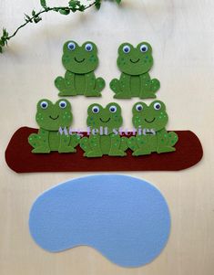 paper cut out of green frogs sitting on top of a red board