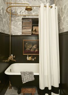 a black and white bathroom with a bathtub, shower curtain, bookshelf and pictures on the wall