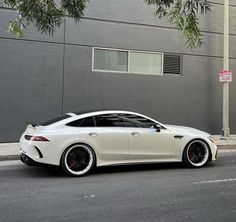 a white car parked on the side of a road next to a tall gray building