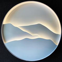 a round plate with mountains in the center on a black tablecloth covered flooring