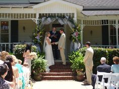 a bride and groom standing at the end of their wedding ceremony in front of a house