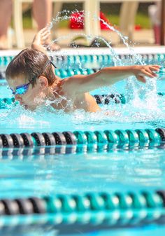 a young boy swimming in a pool wearing goggles