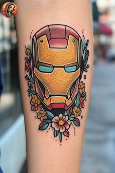 an iron man tattoo on the leg with flowers and leaves around it's head