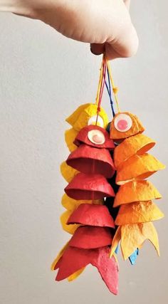 a person is holding up some colorful paper fish ornament hanging from a string