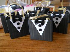 four small black and white bags with gold bow ties on them sitting on a table