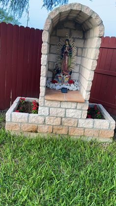 an outdoor shrine in the grass near a fence