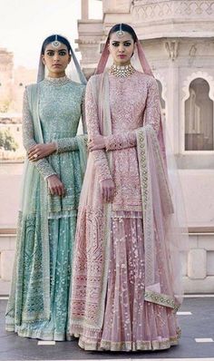 two brides in paste green and pink outfits standing next to each other on the street