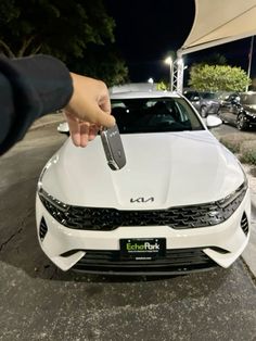 a person holding a car key in front of a white car