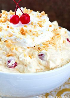 a bowl filled with whipped cream and cherries on top of a yellow table cloth