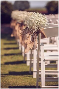 the aisle is lined with white chairs and baby's breath flowers