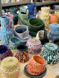 many different colored vases sitting on top of a wooden table next to each other