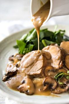 someone pouring gravy onto a plate of mushrooms and greens