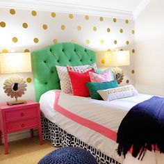 a bedroom decorated in pink, green and gold with polka dot wallpaper on the walls