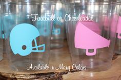 plastic cups with football helmets on them are sitting on a wooden table and the words football or cheerleader available in many colors