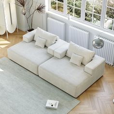 a white couch sitting on top of a wooden floor next to a radiator