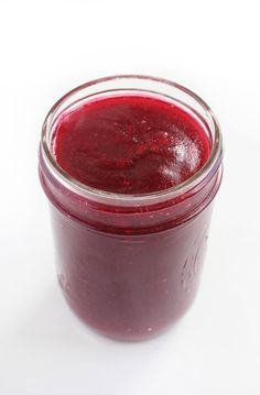 a jar filled with red liquid sitting on top of a white table