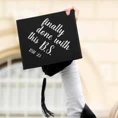 a person holding up a graduation cap that says, finally done with this b's