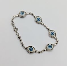 Five blue eyes are featured on this vintage bracelet. The 'eyes' are joined by silver ball links with a spring-ring clasp. Measuring 7.5" long, with each eye measuring about .50" wide. In excellent condition from the 1970s, weighing 14g. Some believe this type of bracelet can ward off evil spirits. B2_543 Goth Evel Eye Bracelets, Metal Evil Eye Bracelet, Blue Metal Evil Eye Bracelet, Blue Eye Bracelet, Bracelet Evil Eye, Bracelet Blue, Vintage Bracelet, Blue Eye, Bracelet Vintage