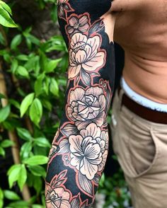 a man's arm with flowers on it and leaves in the backgroud