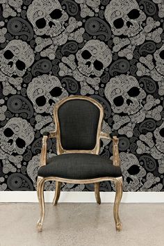 a chair sitting in front of a wall with skulls on it