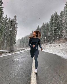 a woman is running down the road in the snow