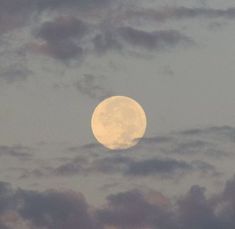 the full moon is seen through some clouds