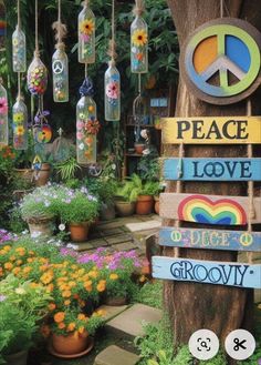 a peace sign hanging from a tree in a garden with potted plants and flowers