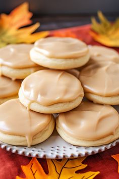 a plate full of cookies with frosting on it and leaves in the back ground