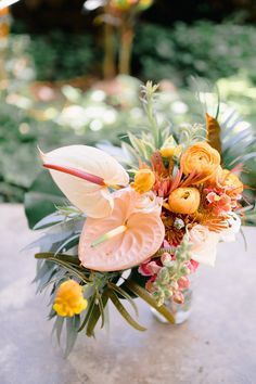 a vase filled with flowers sitting on top of a stone table covered in greenery